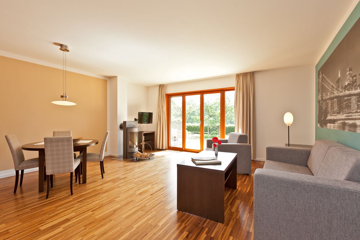 A modern living room with a dining area, a fireplace, and a large window with curtains.