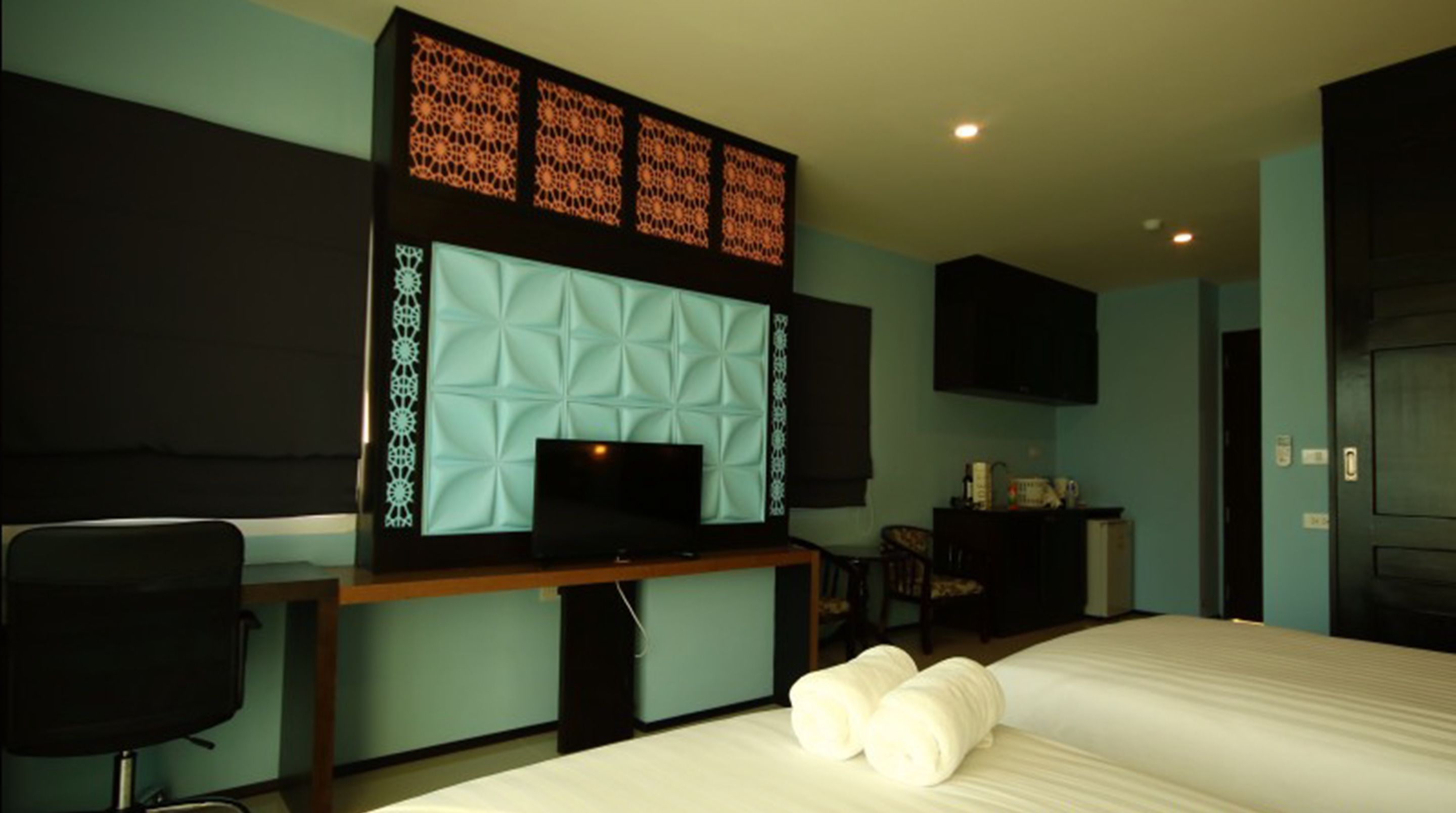 Een hotelkamer met een bed, een bureau met een computer, een televisie en een zithoek.