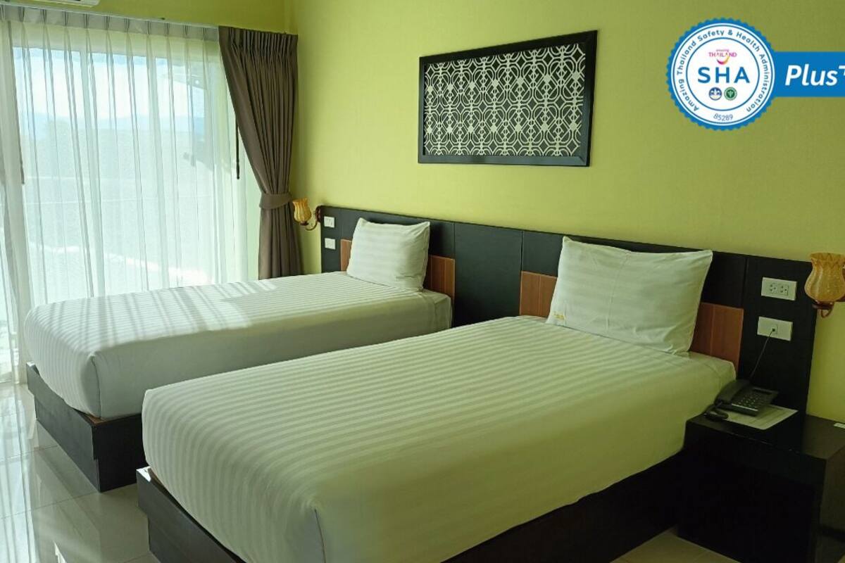 A hotel room with two beds, a nightstand with a phone, and a wall-mounted artwork.