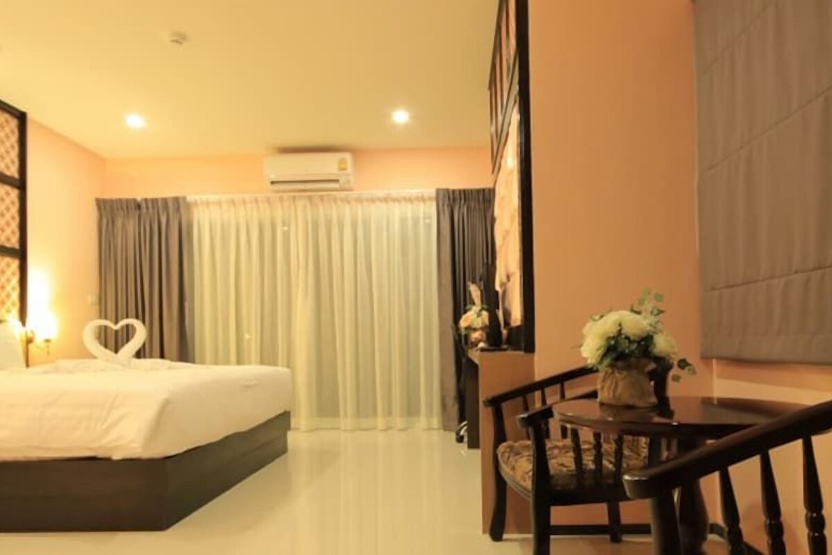 Une chambre d’hôtel avec un lit, un bureau, une chaise et une fenêtre avec des rideaux.