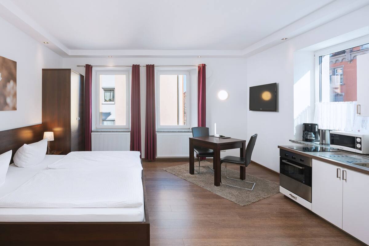 Une chambre d’hôtel équipée d’un lit, d’un bureau, d’une chaise, d’une machine à café et d’un téléviseur.