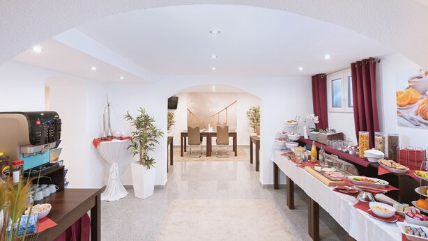 Ein Hotelrestaurant mit Buffet, einer Kaffeemaschine und einer Sitzecke mit einer Hängematte.