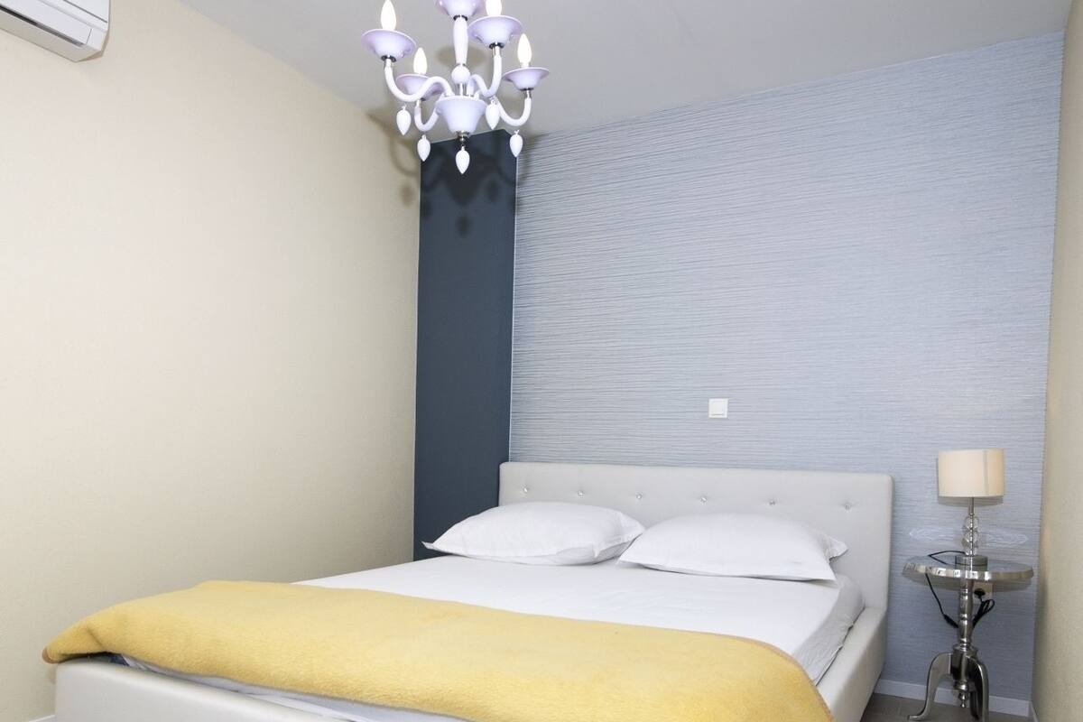 Un dormitorio moderno con una cama, una mesita de noche, una lámpara y un candelabro.