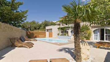 Een seizoensgebonden buitenzwembad, ligstoelen bij het zwembad