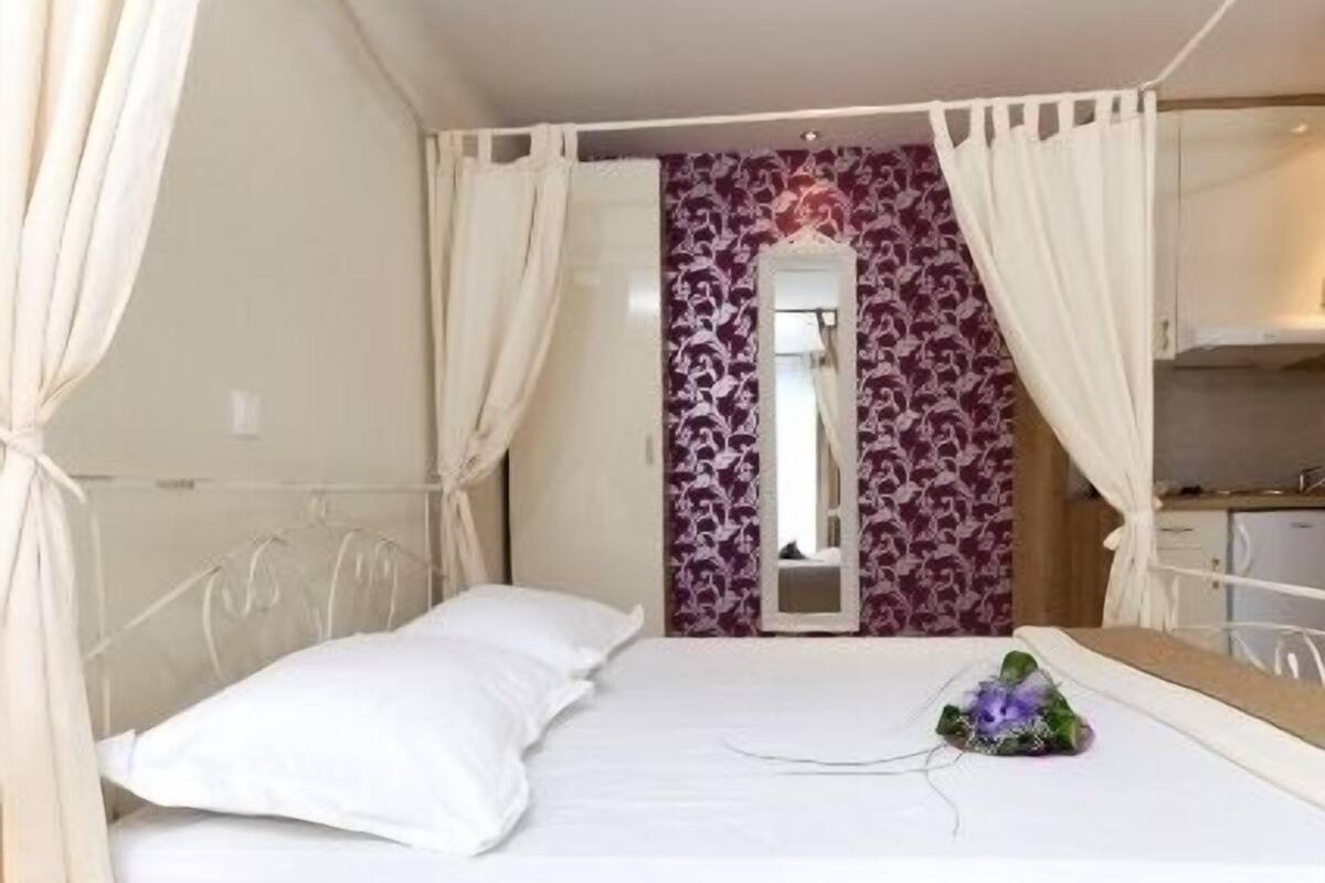 Una cama individual con cabecera, una mesita de noche, un espejo y una pared con estampado floral.