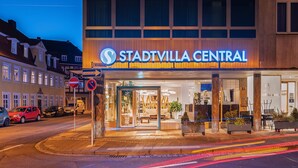 Fachada de un hotel con un cartel que dice "Stadtvilla Central". Hay coches estacionados afuera y una señal de prohibido el paso es visible.