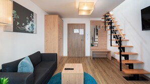 Una sala de estar moderna con un sofá, una mesa de centro, una escalera y una puerta que da a otra habitación.