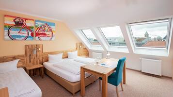 A modern hotel room with a large bed, a wooden desk, and a view of the city through skylights.