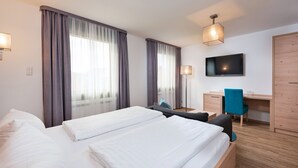 Habitación de hotel con dos camas, un escritorio, una silla, un televisor y un armario.