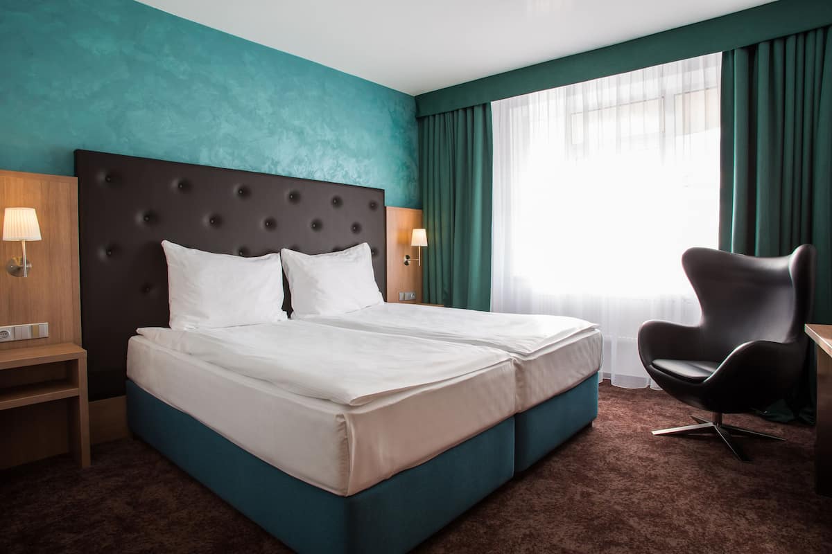 A hotel room with a large bed, a desk, and a chair.