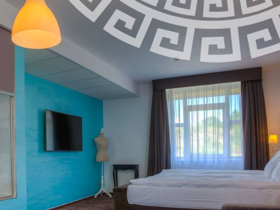 Habitación de hotel con una cama grande, televisión, ducha y vistas al exterior.