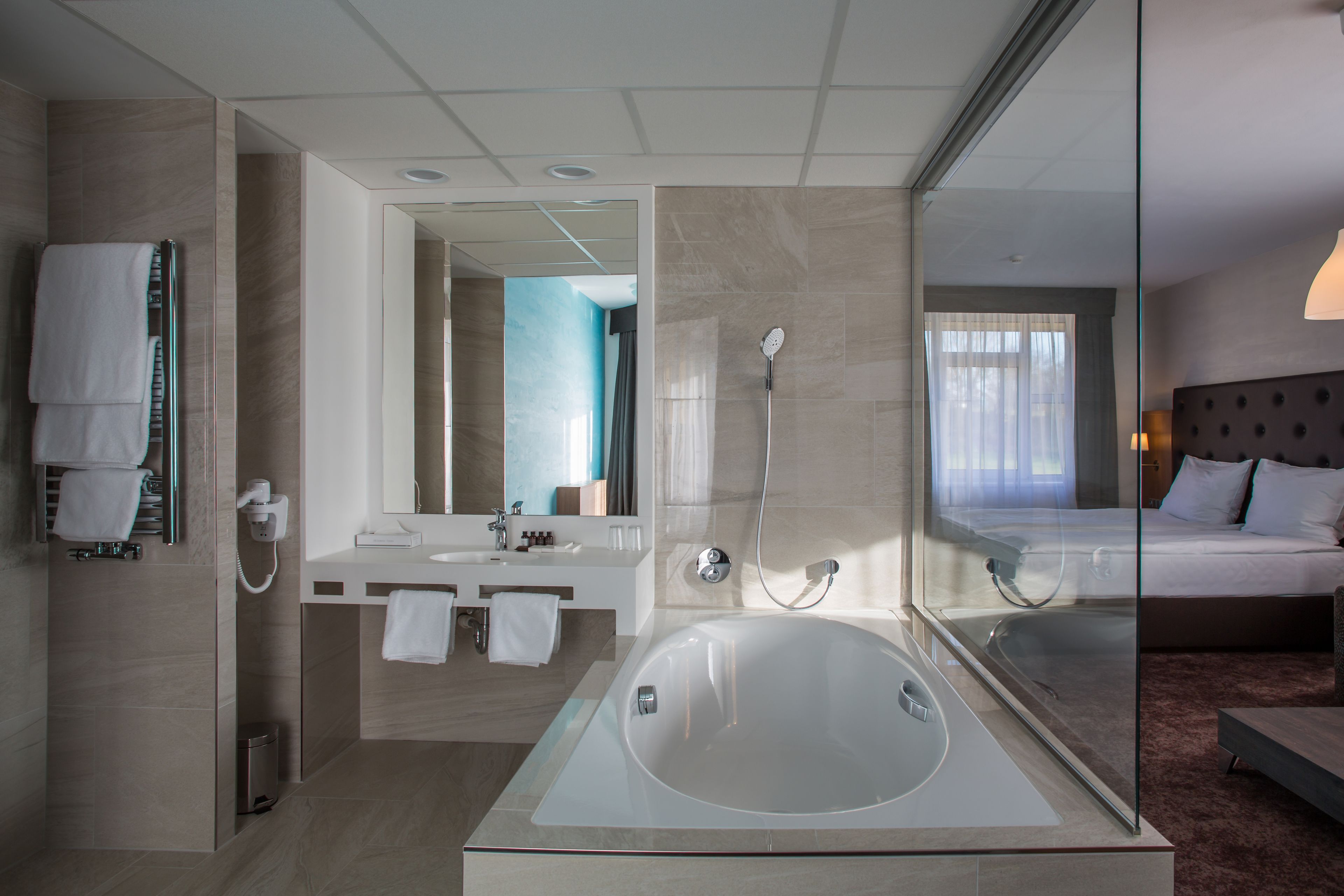 A modern hotel bathroom with a large bathtub, a vanity with a mirror, and a shower.