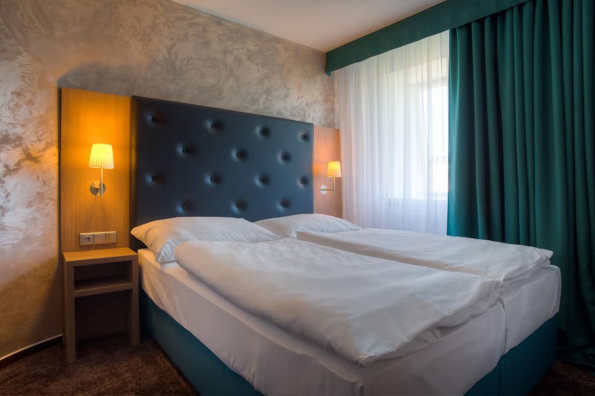A hotel room with a large bed, two bedside tables, and a headboard.