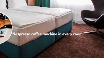 Et hotelværelse med fuld afskærmning, en betrukket sengegavl, en Nespresso-kaffemaskine og en moderne stol.