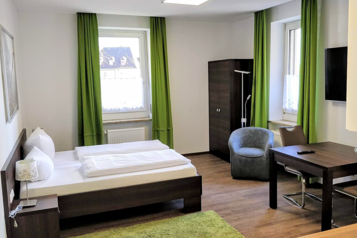 Une chambre d’hôtel équipée d’un lit, d’un bureau, d’une chaise, d’une armoire et d’un téléviseur.