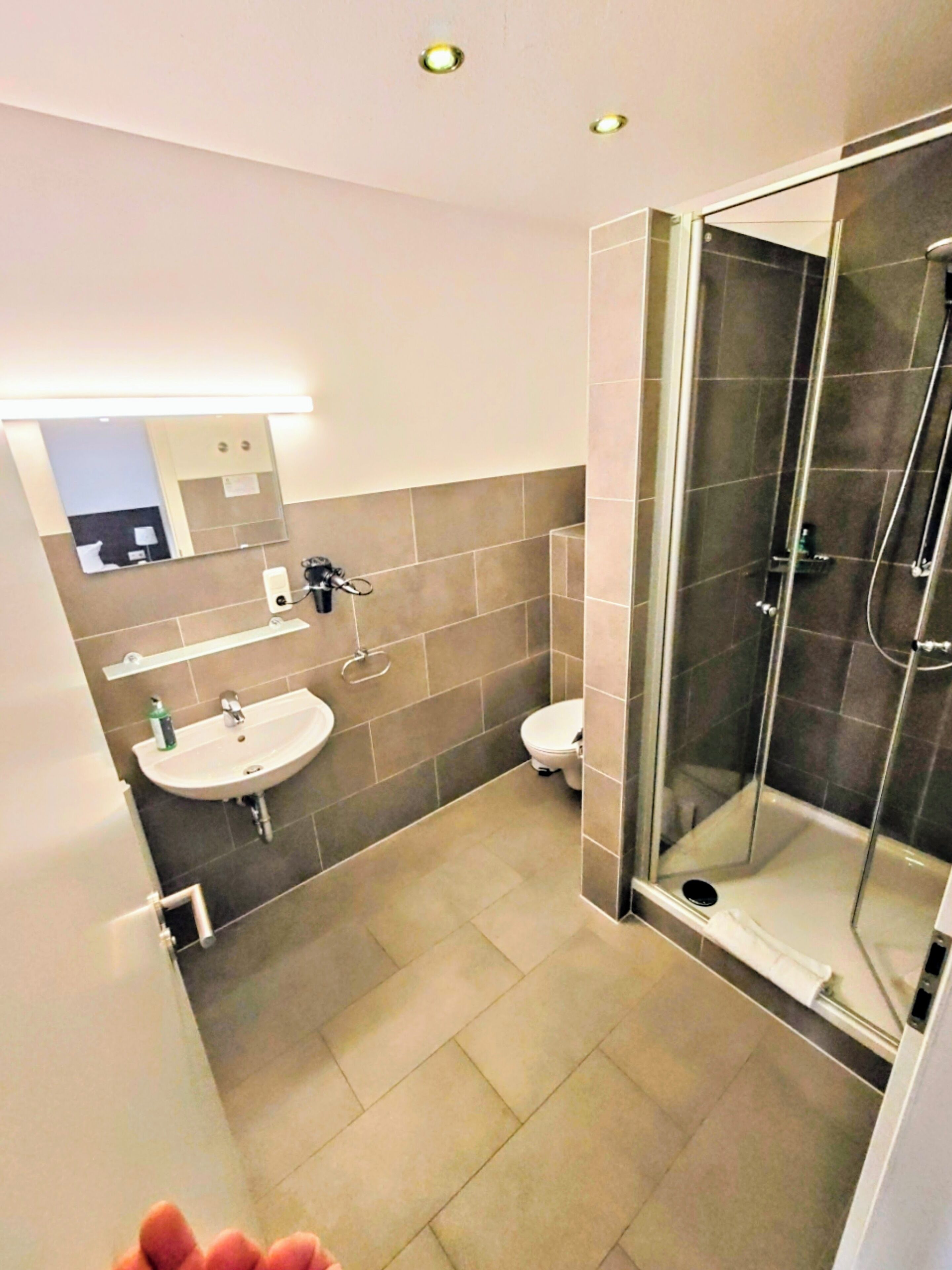A modern bathroom with a glass-enclosed shower, a sink, and a toilet.
