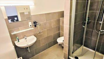 A modern bathroom with a glass-enclosed shower, a sink, and a toilet.