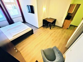 Una habitación de hotel moderna con una cama, un escritorio, una silla y un televisor montado en la pared.
