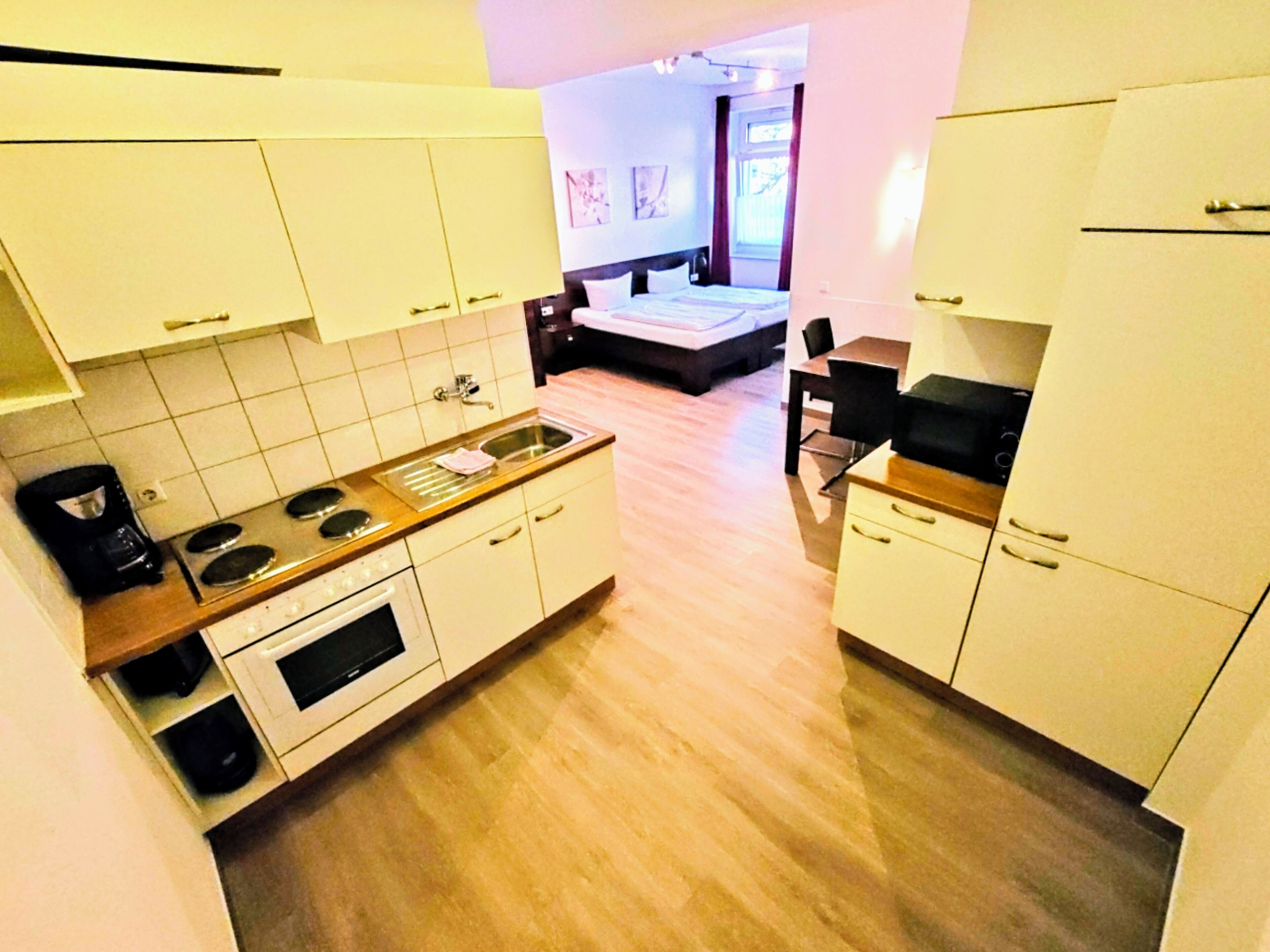 A compact kitchen with white cabinets, a wooden countertop, and a sink.
