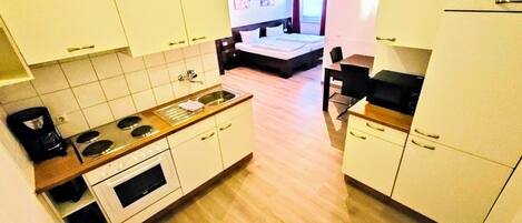 Een kleine keuken met witte kastjes, een houten aanrechtblad en een spoelbak.