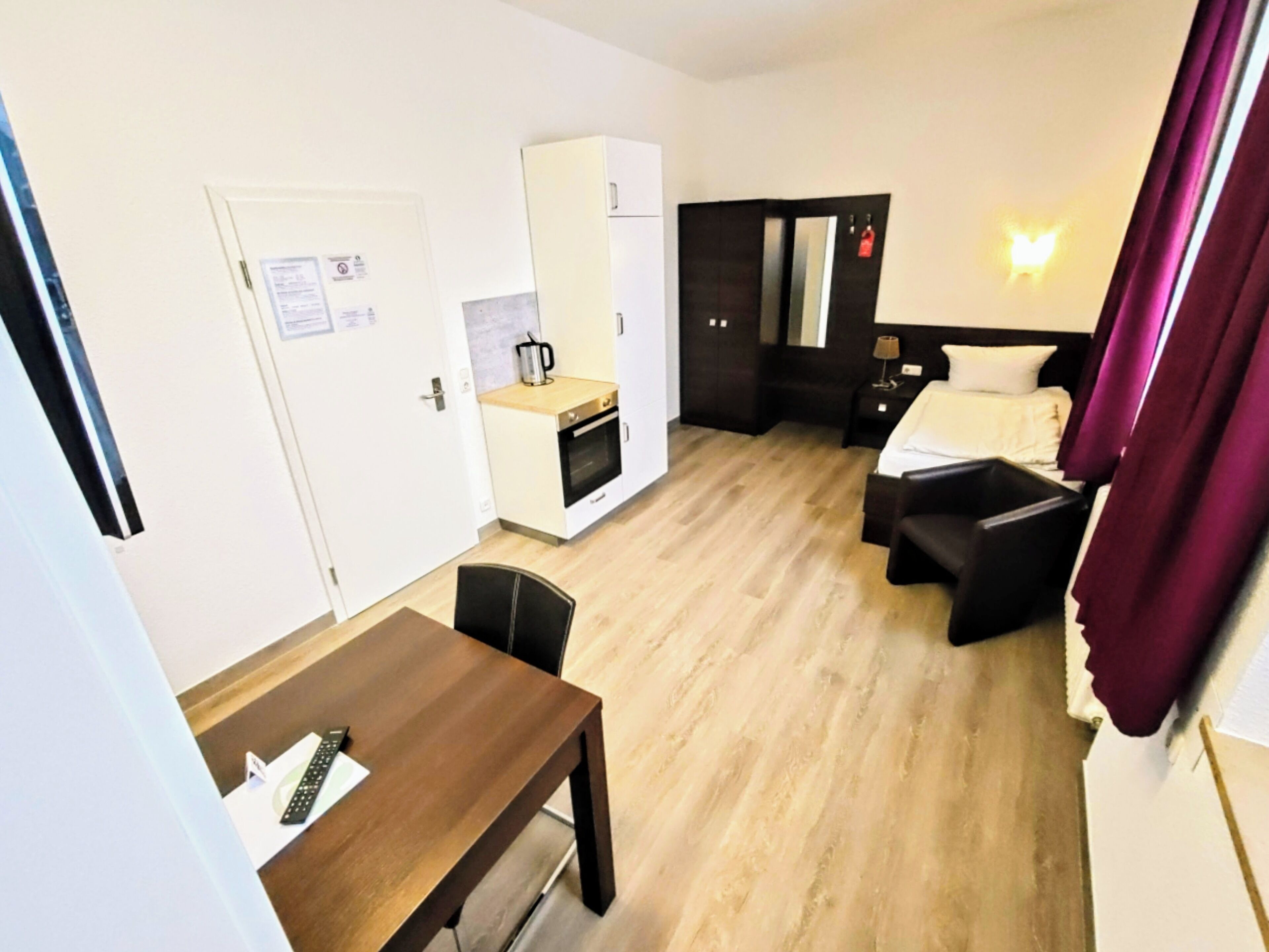 Une chambre d’hôtel compacte comprenant un coin cuisine, un lit et un bureau.