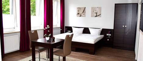 Un dormitorio moderno con una cama, una mesa de comedor con sillas y obras de arte en la pared.