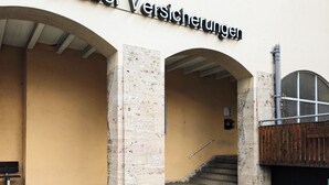 L’entrée d’un immeuble, avec une enseigne indiquant « Hopfauer Versicherungen ».