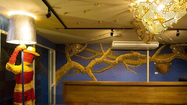 A reception desk with a blue wall and a decorative branch sculpture. - Non Nid Non Noi Design Residence (Chiang Mai)