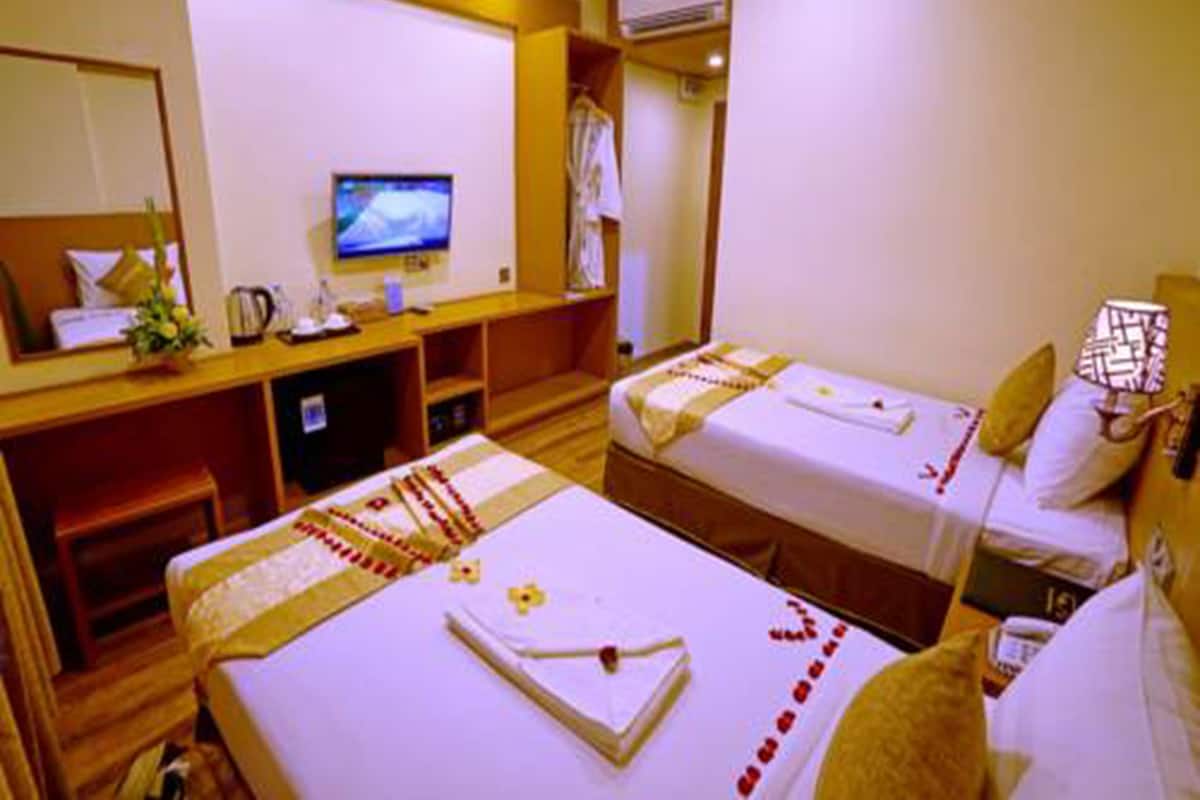 Habitación de hotel con dos camas, un escritorio, un televisor y un aire acondicionado.