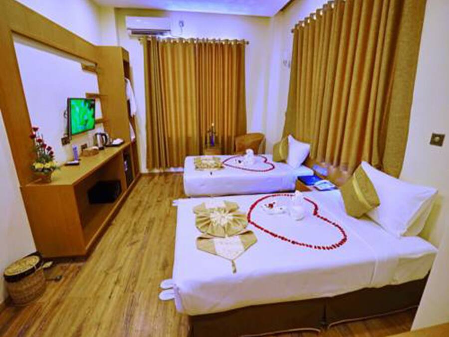 A hotel room with two beds, a desk with a computer, and curtains.