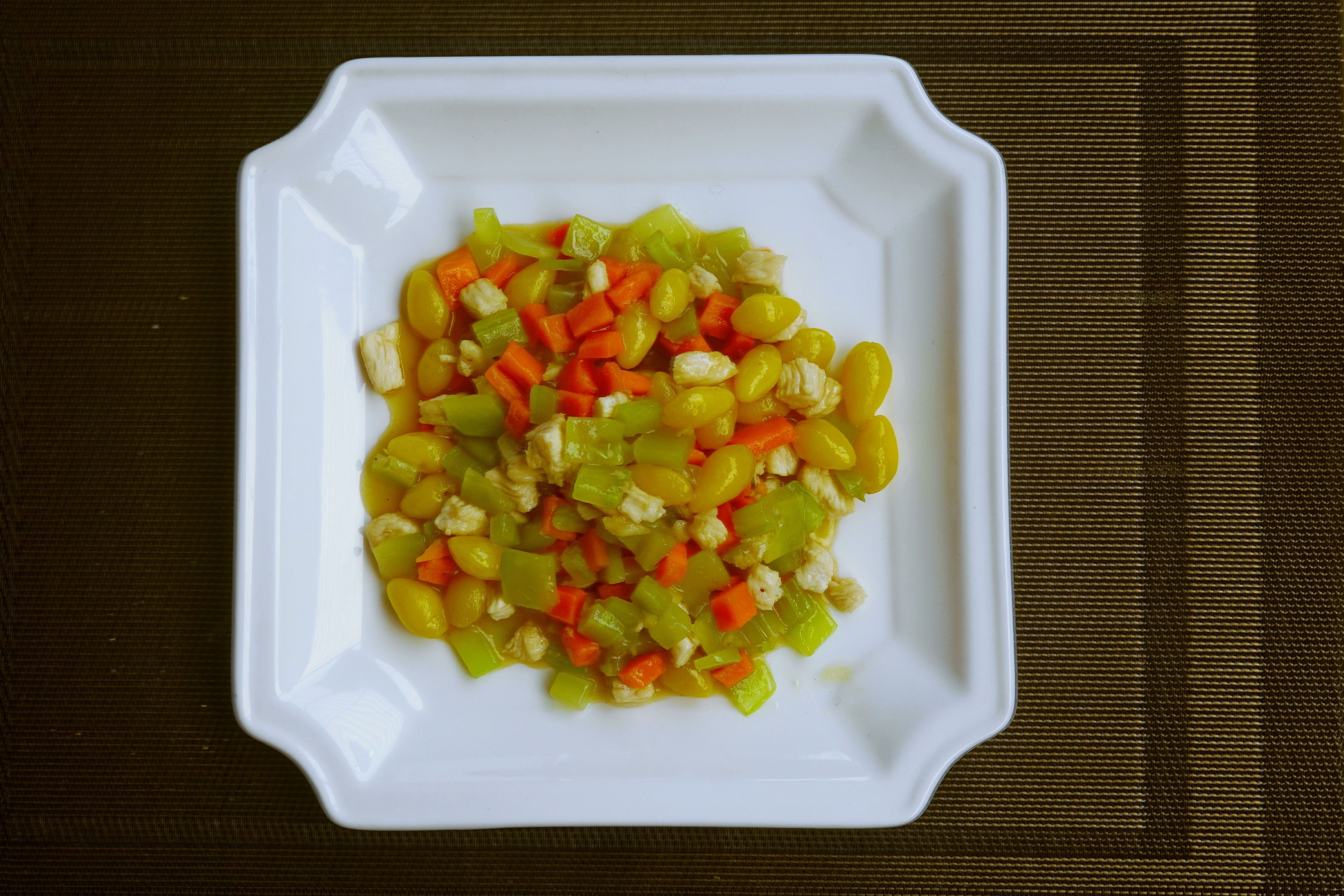 A white plate with a colorful vegetable salad on a dark textured surface.