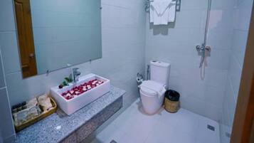 Un baño moderno con encimera de granito, un lavabo blanco, un inodoro y una ducha.
