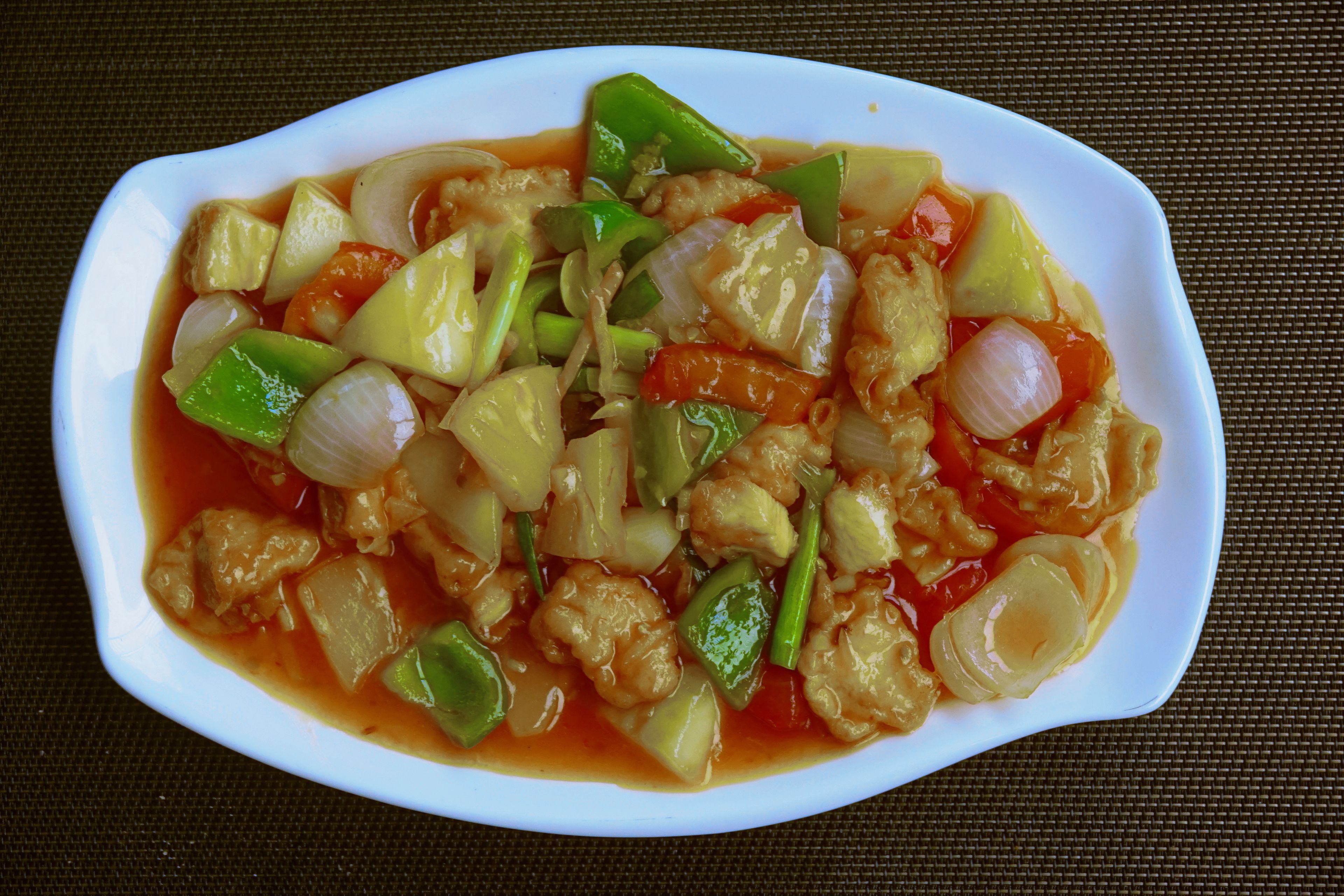 Un tazón blanco y ovalado con salteado de verduras y tofu.