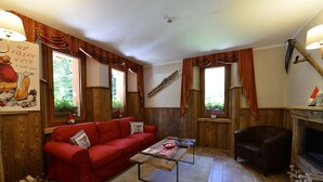 A cozy living room with a red sofa, a coffee table, and a fireplace. - Albergo Herbetet (Cogne)