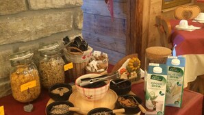 A breakfast buffet with various food items and a clock on the wall. - Albergo Herbetet (Cogne)