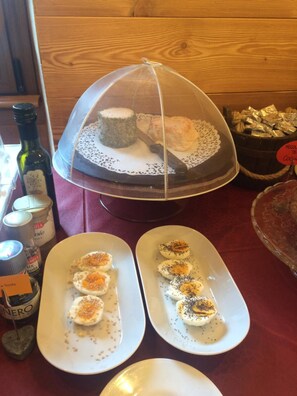 Una mesa con un plato cubierto que contiene un panecillo y un cuchillo, dos platos con medio huevo cubierto de semillas y un bol de aperitivos.