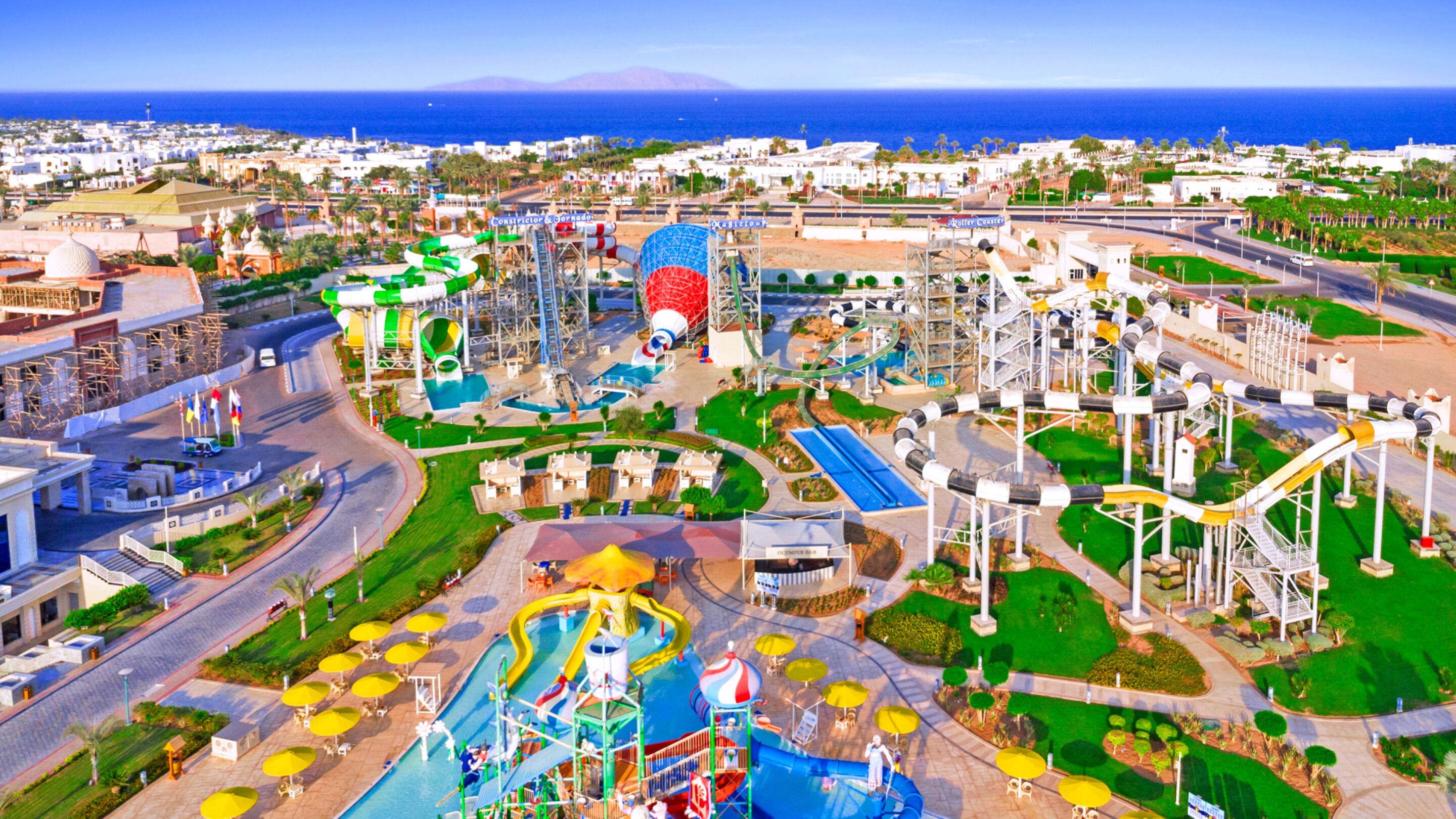 Un parque acuático con múltiples toboganes y piscinas, rodeado de vegetación y edificios.