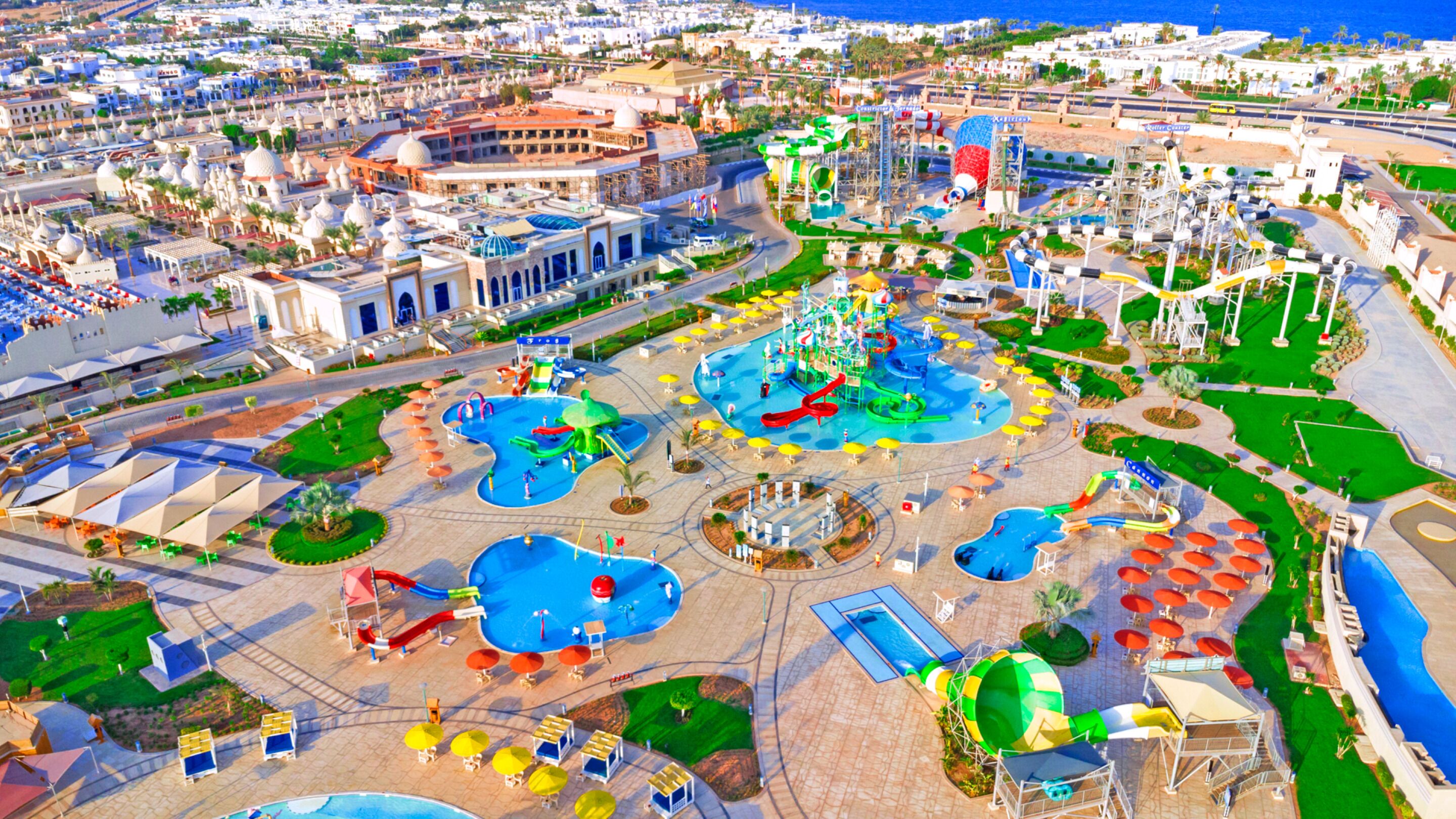 An aerial view of a resort with multiple pools, water slides, and a large building with domed architecture.