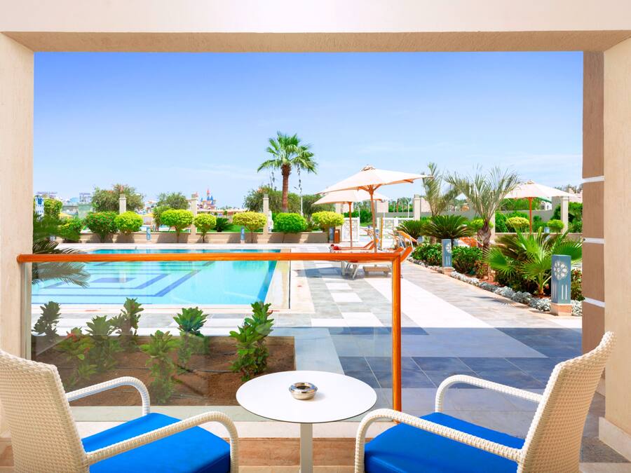 Varanda com vista para uma piscina, cercada por vegetação e palmeiras.