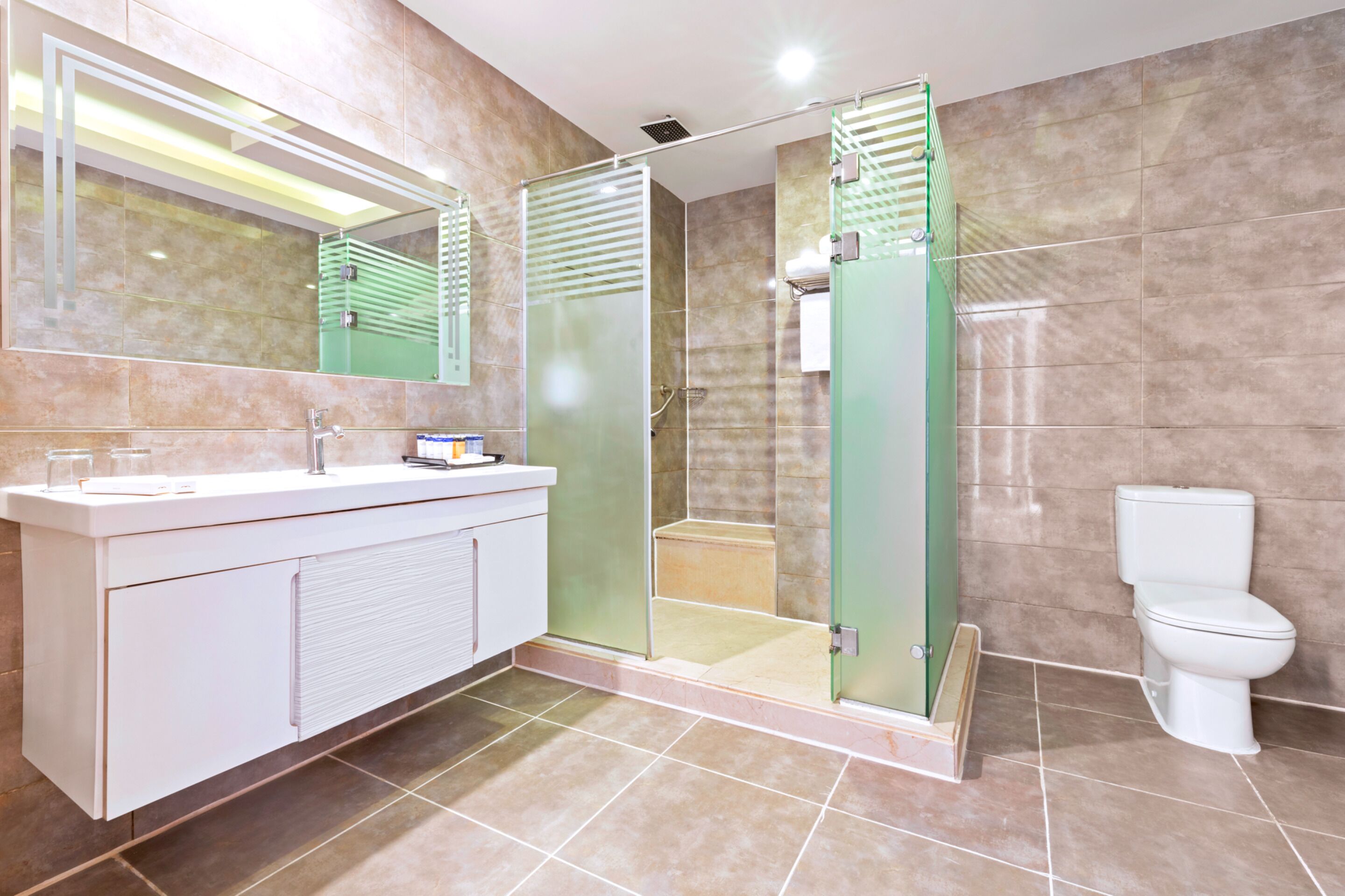 Un baño moderno con ducha de vidrio, un lavamanos blanco y un inodoro.
