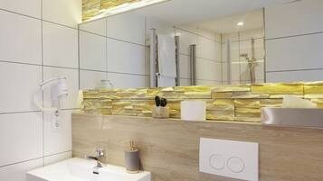 A modern bathroom with a white sink, a stone backsplash, a mirror, and a shower.