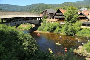 Un río con kayaks, un puente de madera y edificios tradicionales con balcones.