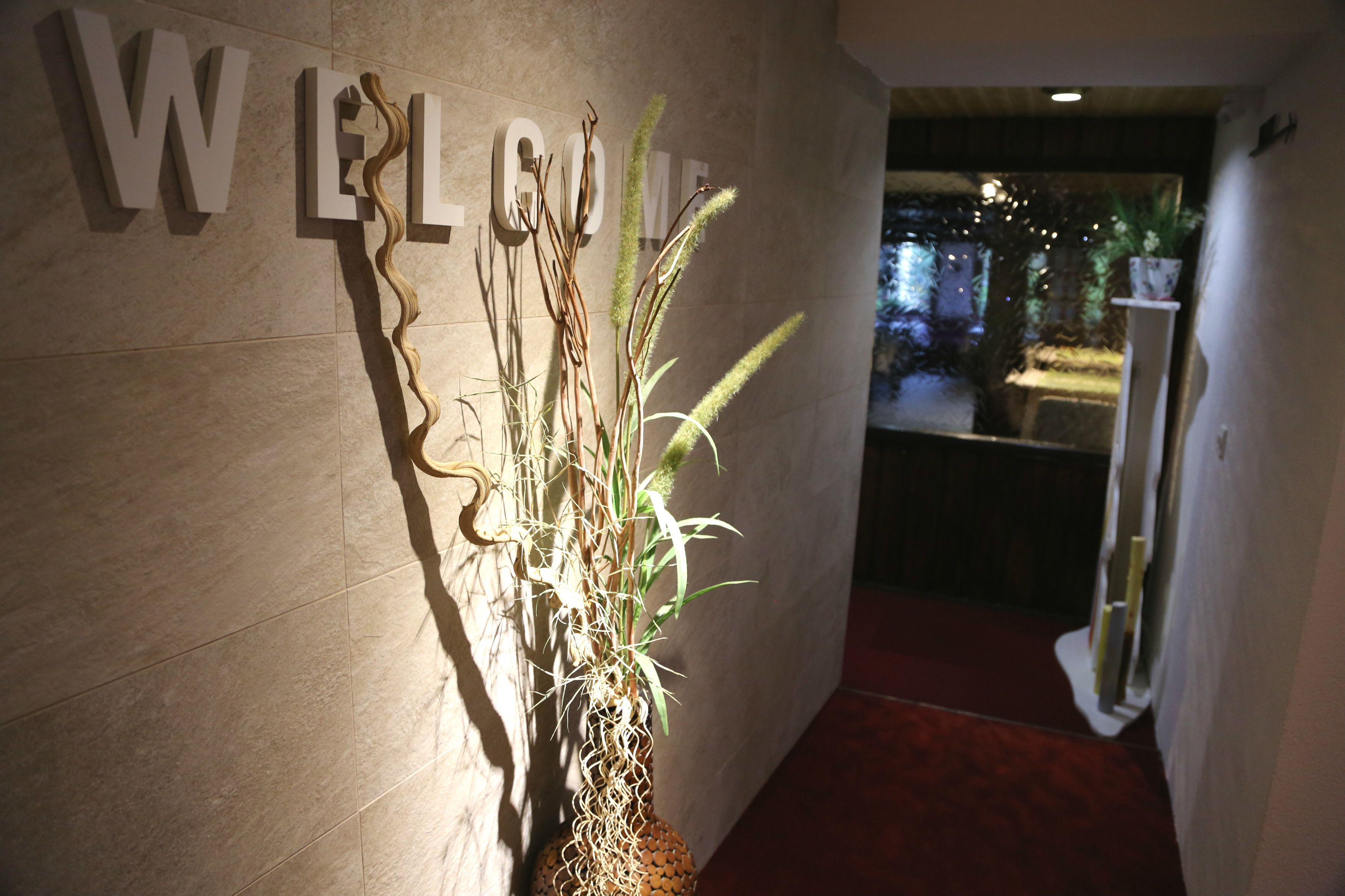A welcome sign with a decorative plant beside it.