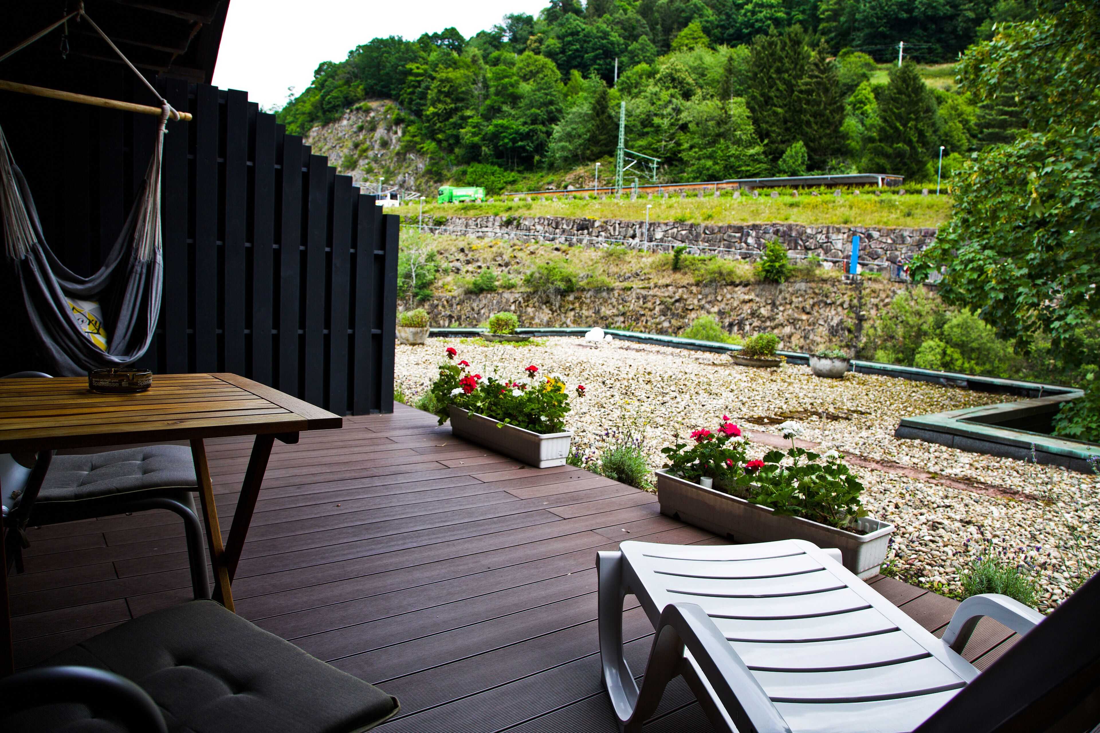 A wooden deck with outdoor furniture, including a table and chairs, and flower planters.