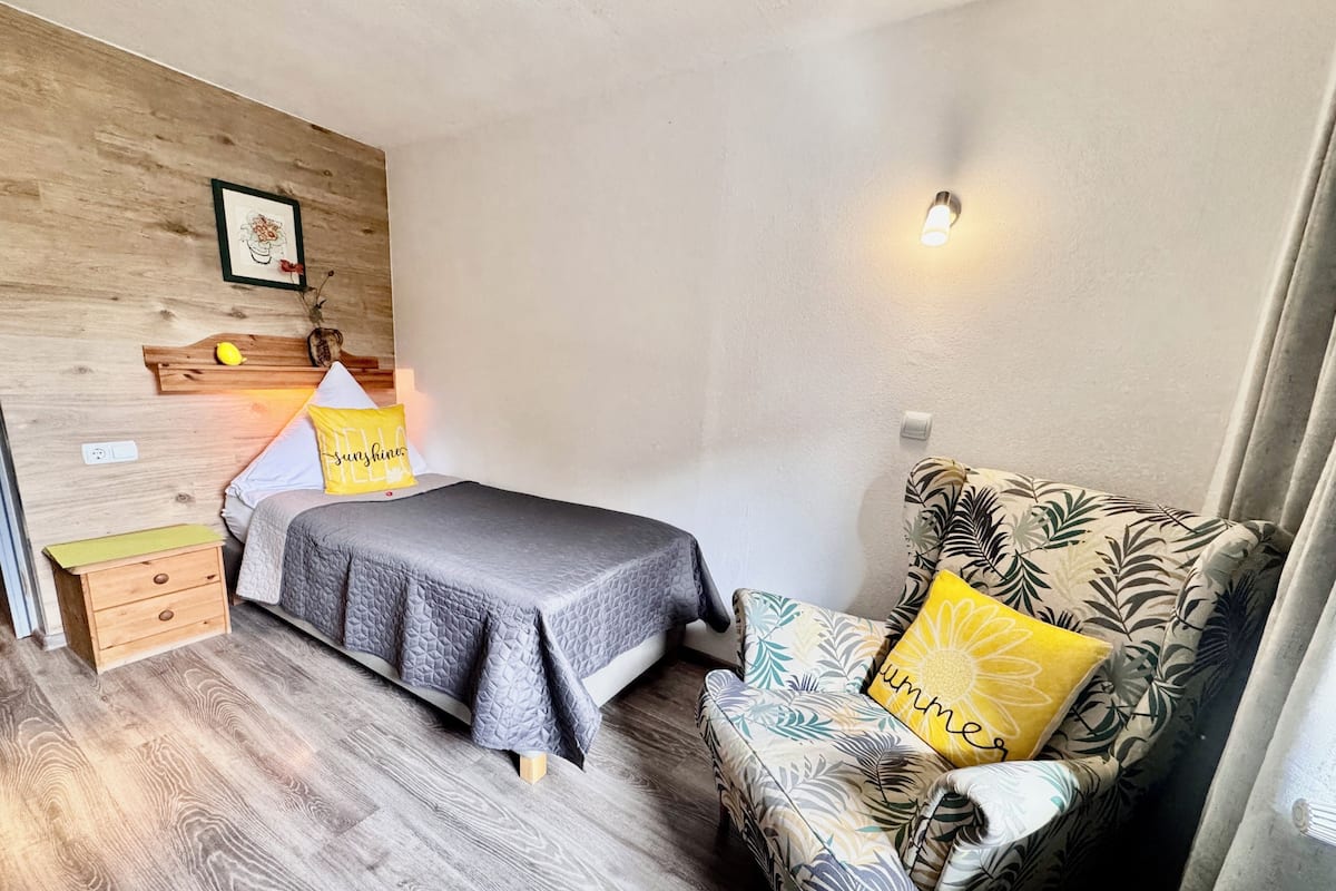 Un dormitorio con cama, mesita de noche, lámpara y un sofá estampado con motivos florales.