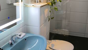 Ein Badezimmer mit blauem Waschbecken, weißer Toilette und einer Duschkabine aus Glas.