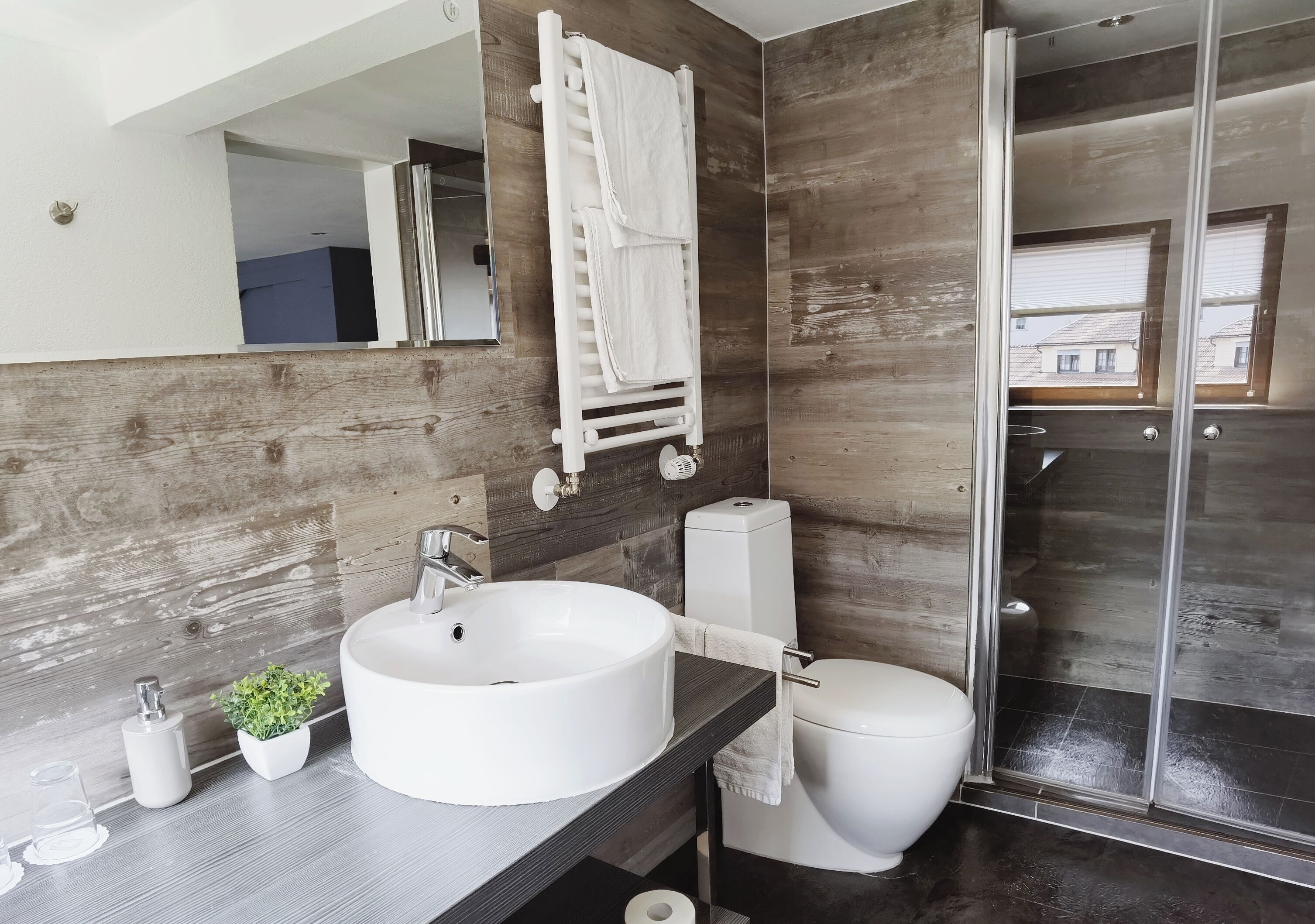 A modern bathroom with a large white sink, a toilet, and a glass shower enclosure.