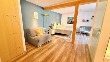 A modern living room with a sofa, a bed, a coffee table, and a dining area.