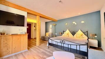 Een slaapkamer met een bed, nachtkastjes, een televisie, een stoel en een bureau.