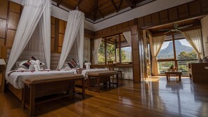 A room with a wooden floor, a bed with a canopy, a bench, and a table. - Popa Garden Resort (Kyaukpadaung)